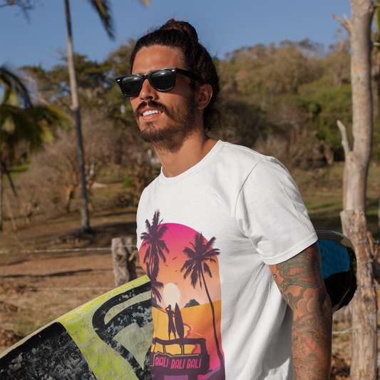 Man wearing sunglasses and a white t-shirt with a colorful graphic, holding a surfboard, standing outdoors.