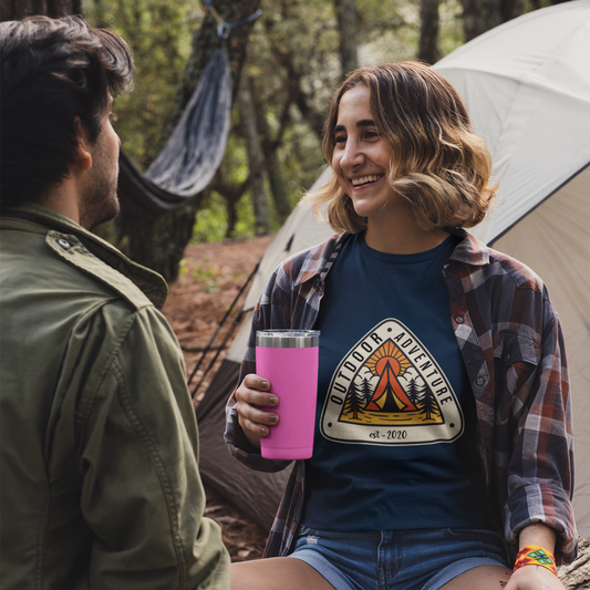 Two people sitting outdoors near a tent, one holding a pink cup.