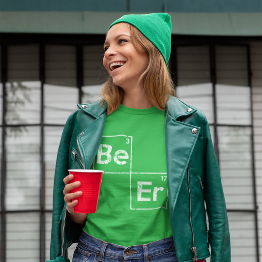 Person wearing a green shirt with 'Be Er' text, green beanie, and leather jacket holding a red cup.