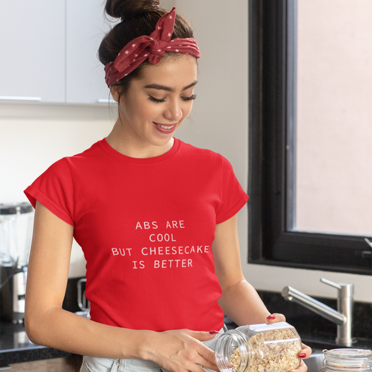 Woman in a kitchen wearing a red t-shirt with text, preparing food.