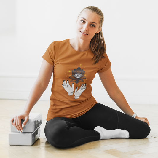 Woman sitting on the floor with a box, wearing a brown t-shirt with a graphic design.