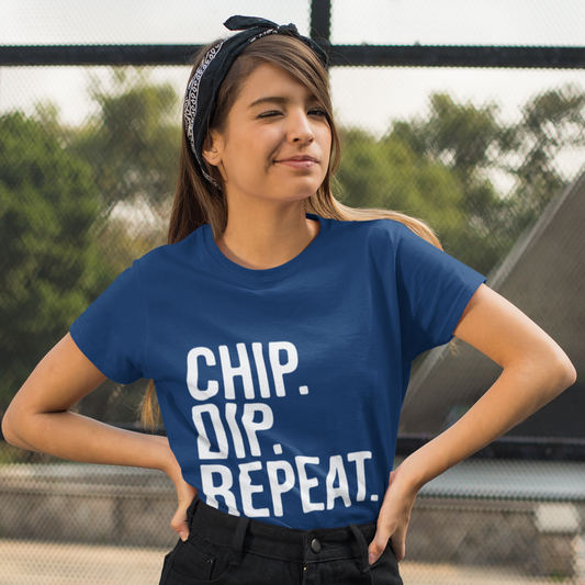 Woman wearing a blue t-shirt with 'CHIP. DIP. REPEAT' text, standing outdoors.