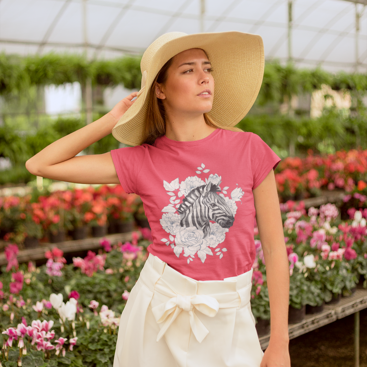 Woman wearing a pink t-shirt with a zebra design in a greenhouse setting