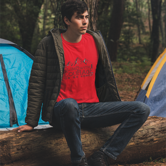 Person sitting on a log in a forest with camping tents in the background