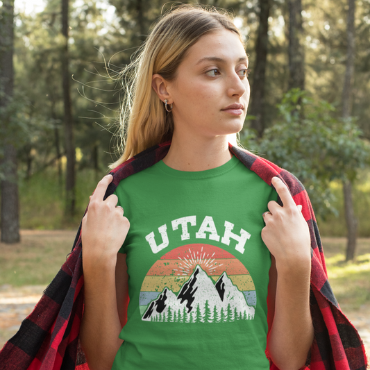 Woman wearing a green 'Utah' t-shirt with mountain design in a forest setting