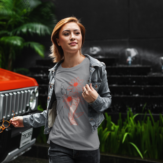 Woman wearing a gray t-shirt with a red heart design in front of an orange vehicle.