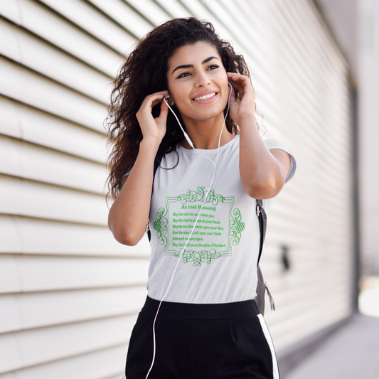 Woman wearing a white t-shirt with green text and headphones, standing against a light-colored wall.