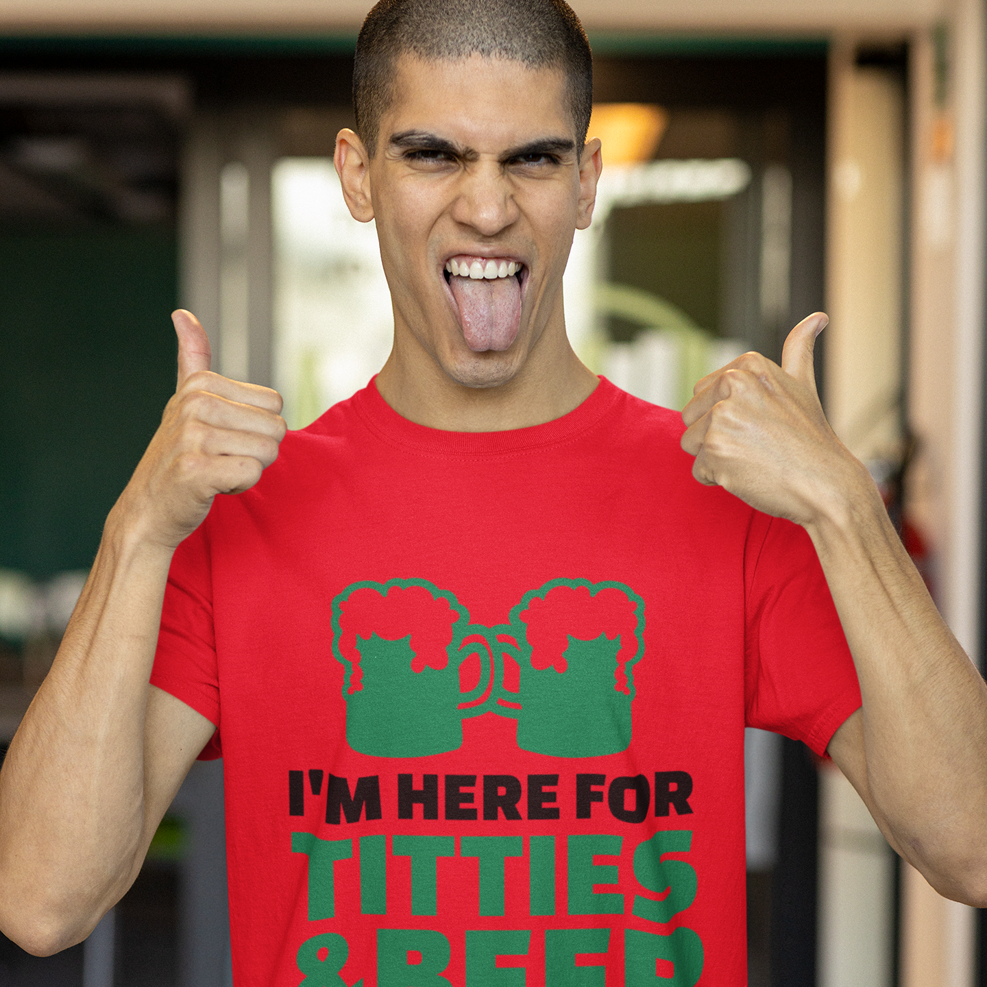 Man wearing a red t-shirt with green text and graphics, giving a thumbs-up gesture.