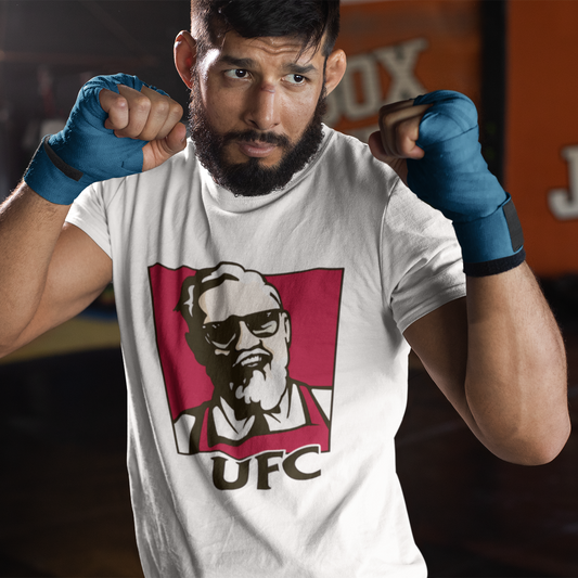 Person wearing a UFC t-shirt with a logo, posing in a gym setting.