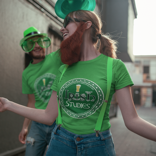 Two people wearing green shirts with 'Irish Studies' text, one person also wearing green suspenders, outdoors.