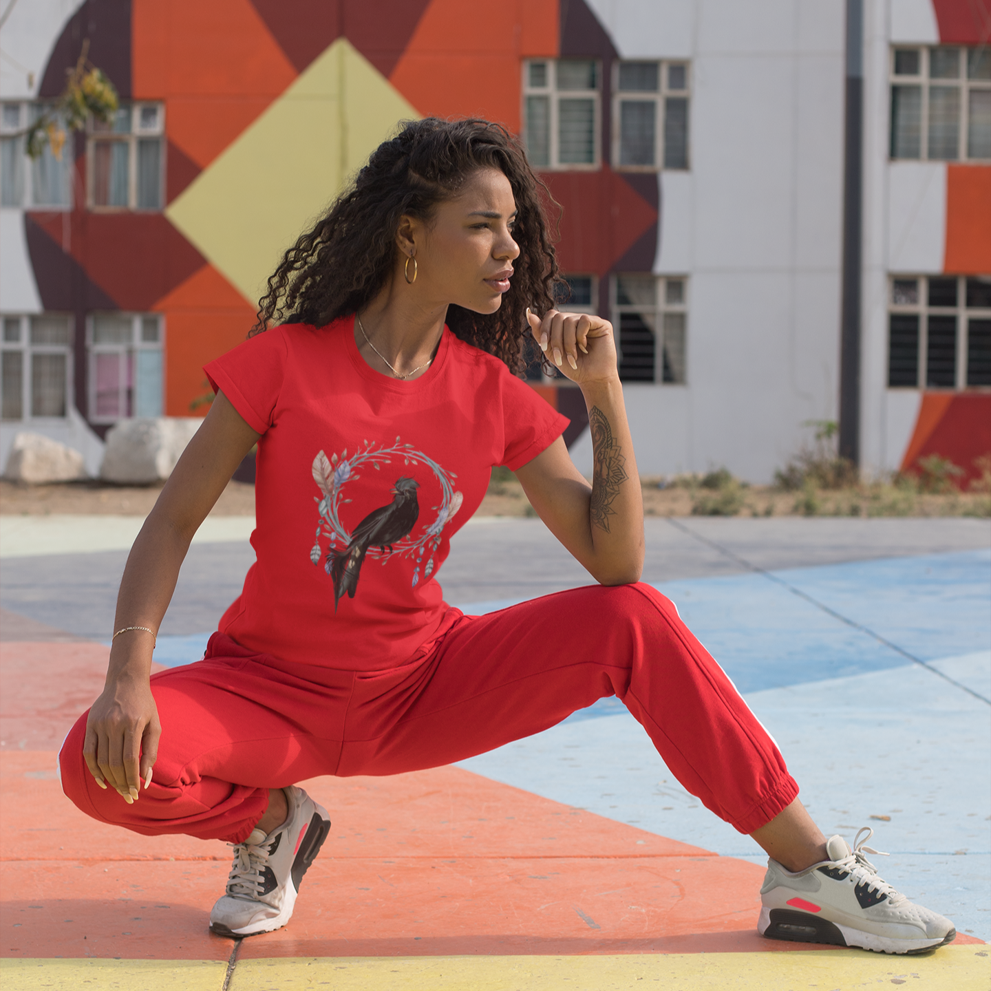 Woman in red outfit posing on a colorful pavement with a geometric mural in the background