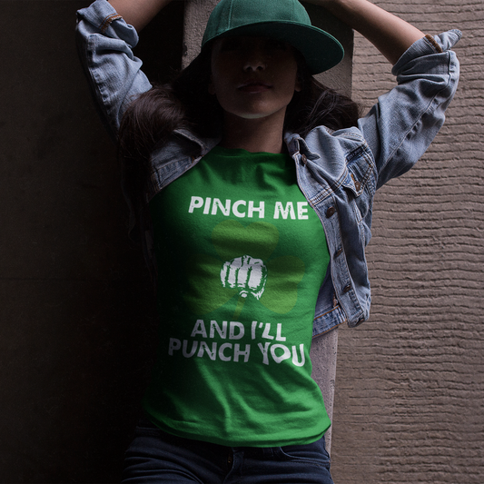 Person wearing a green t-shirt with text and a graphic, standing against a textured wall.