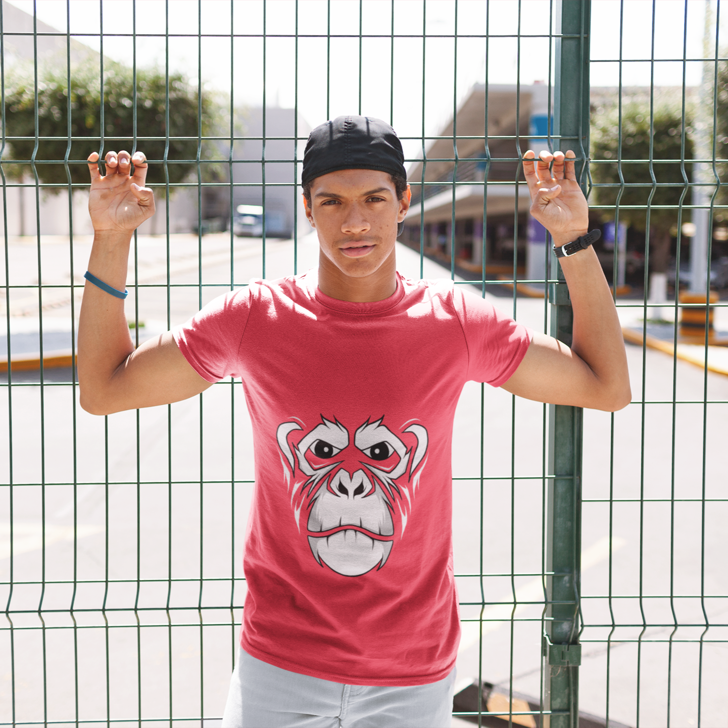 Person wearing a pink t-shirt with a monkey graphic design, standing behind a wire fence.