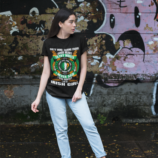 Person wearing a black t-shirt with colorful graphics and text, standing in front of a graffiti-covered wall.