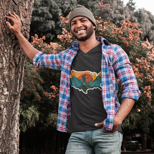 Man leaning against a tree with a colorful shirt and black t-shirt with a graphic design.
