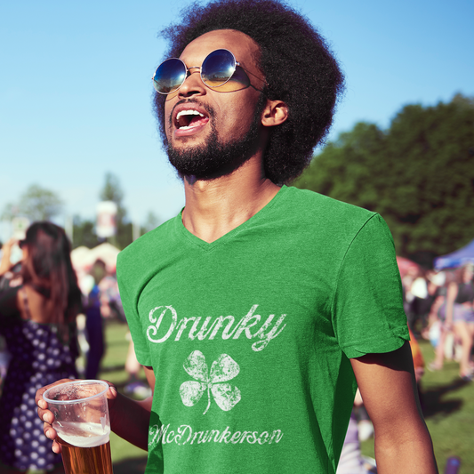 Man wearing a green t-shirt with 'Drunky' text, holding a beer at a festival.