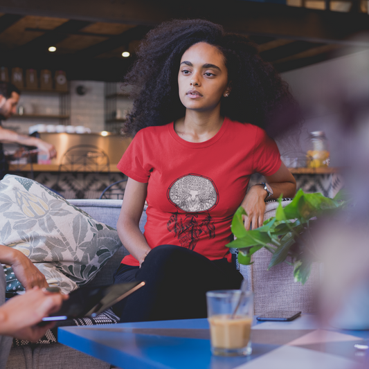 Woman in a red shirt sitting on a couch with a plant in a cafe setting